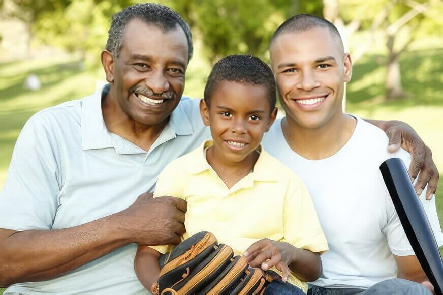 Image of a grandfather, son and grandson with baseball bat and glove.